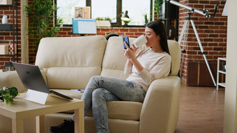 快乐的年轻的成人人发短信朋友坐着沙发内部公寓