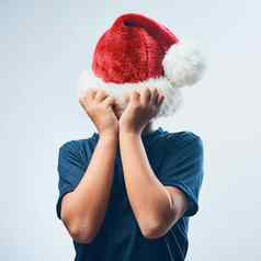 圣诞节取消了工作室拍摄可爱的男孩覆盖头圣诞老人他灰色背景