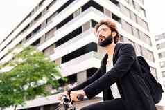 时尚的有胡子的男人。骑自行车城市