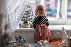 女孩坐着床上窗口装修小树小圣诞节玩具快乐健康的孩子庆祝传统的家庭假期可爱的婴儿