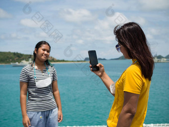 女人黄色的衬衫持有电话图片女孩灰色的衬衫背景蓝色的水小山旅游电晕病毒爆发