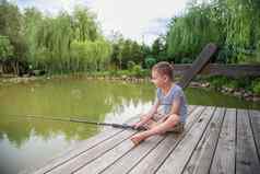 伤心男孩坐在湖捕获鱼国际孩子们的一天