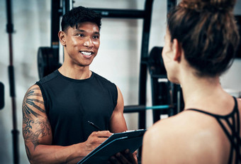 让快速身体评估运动年轻的女人会说话的健身教练健身房
