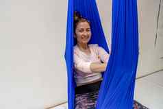 年轻的女人提出了反重力空中瑜伽蓝色的吊床白色背景