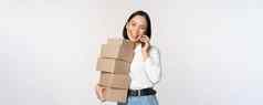 图像年轻的亚洲女商人回答电话调用携带盒子交付摆姿势白色背景