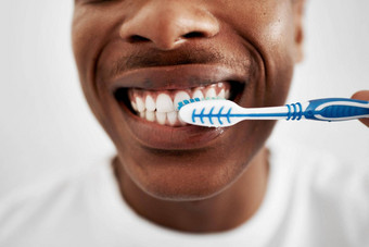刷长牙齿保持健康的年轻的男人。刷牙牙齿浴室首页