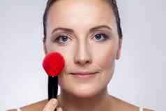 女人适用于脸红化妆刷使在乎脸皮肤相机