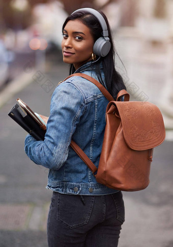 开始未来今天年轻的女人走城市穿耳机携带书