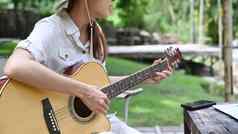 年轻的女人玩吉他野营自然公园美丽的一天旅行冒险假期概念