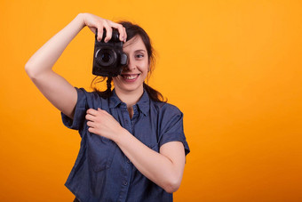 女人摄影师采取图片数码单反相机相机工作室黄色的背景