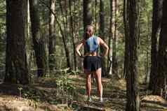 后视图女小道跑步者穿着运动服装站小道森林准备运行