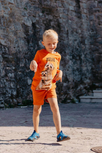 儿童<strong>户外</strong>活动微笑蹒跚学步的男孩穿橙色短裤跳运行有趣的后院阳光明媚的热<strong>夏天</strong>一天完整的长度精力充沛的男孩时尚的休闲装跳<strong>户外</strong>