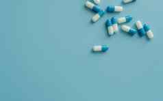 前视图蓝白色抗生素胶囊药片蓝色的背景处方药物抗生素药物电阻制药行业制药护理制药学概念抗菌药物