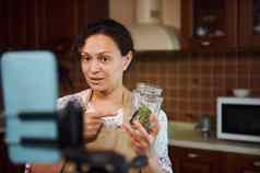 迷人的女人视频博主显示Jar烹饪草本植物相机记录内容食物博客