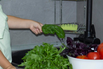 <strong>男孩短发</strong>型帮助烹饪厨房洗新鲜的蔬菜草本植物黑色的水槽灰色的厨房