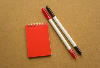 红色的记事本笔记红色的表空白空间笔记灭克磷记号笔红色的黑色的温暖的赭色灰色的背景假期日历笔记记事本