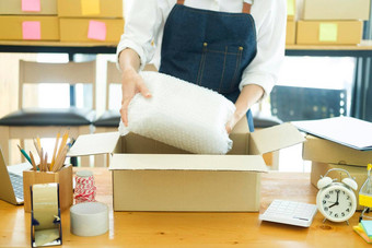 亚洲女衣服商<strong>店老板</strong>折叠t恤包装纸板包裹盒子