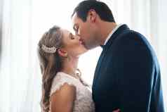 密封吻充满深情的年轻的夫妇站在室内接吻婚礼