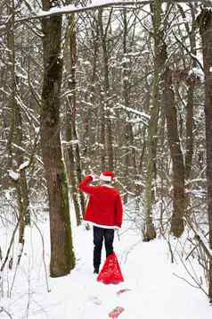 传统的圣诞老人老人穿他拖大红色的袋礼物森林