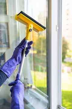 房子清洁清洁概念年轻的女孩紫色的手套黄色的拖把手洗窗口