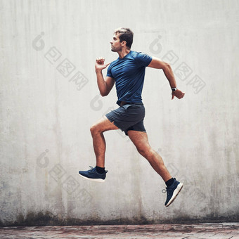 跳过障碍<strong>达到目标</strong>运动年轻的男人。运行灰色墙在户外