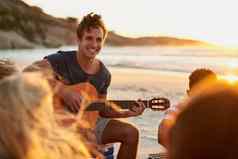 音乐海洋男人。玩吉他坐着海滩朋友