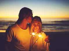 时刻使光荣的光爱年轻的夫妇玩罗马焰火筒海滩晚上