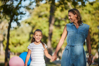 有趣的一天公园可爱的女孩持有气球走公园妈妈。