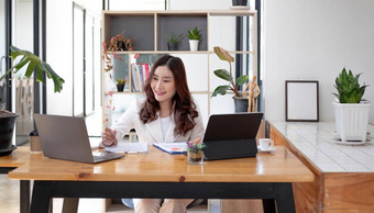 美丽的年轻的亚洲女人坐着咖啡商店移动PC快乐年轻的女商人坐着表格咖啡馆选项卡前电脑