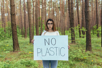 年轻的女积极分子站森林塑料<strong>海报志愿者</strong>苦苦挣扎的森林污染