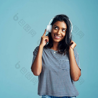令人惊异的能认同音乐美丽的年轻的女人穿耳机蓝色的背景