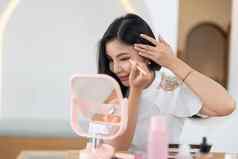 美博主概念美丽的可爱的亚洲年轻的女人女孩化妆脸应用刷眼睛眉眼影镜子首页女自然时尚风格