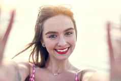 采取自拍海肖像美丽的年轻的女人采取自拍海滩