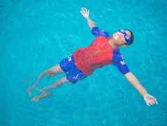 男孩穿泳衣眼镜游泳中间池蓝色的水背景