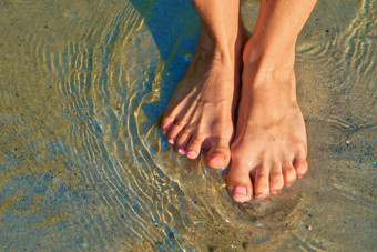 可爱的女孩的腿脚站清晰的透明的水