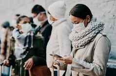 人游客旅行科维德站行公共旅行设施穿保护面具女人队列阅读社会媒体新闻冠状病毒流感大流行电话