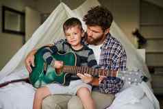 学习玩吉他裁剪肖像可爱的男孩坐着爸爸腿上学习玩吉他首页