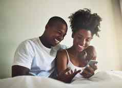 分享社会媒体账户快乐年轻的夫妇移动电话床上首页