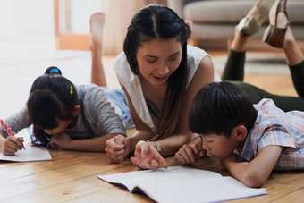 教学孩子们家庭作业快乐的妈妈。孩子们家庭作业说谎地板上首页一天