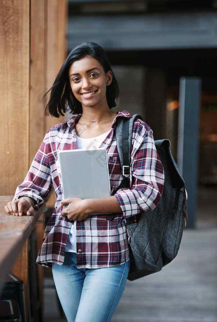 爱校园生活裁剪肖像有吸引力的年轻的女学生持有教科书站校园