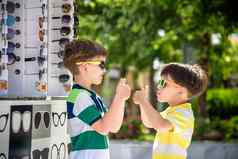孩子选择太阳镜男孩站sun-proof眼镜背景商店窗口眼镜孩子选择太阳镜出售夏天职业