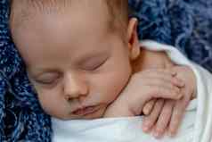 新生儿婴儿脸特写镜头睡觉新生儿男孩白色针织毯子谎言蓝色的皮毛