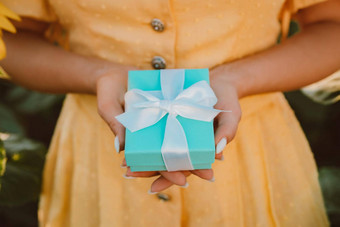 女人持有蓝色的礼物盒子弓向日葵场现在奖金提供概念手温暖的黄色的爽肤水时尚的