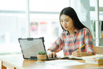 年轻的亚洲女人研究前面移动PC电脑耳机离线