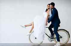度蜜月工作室拍摄新结婚了年轻的夫妇骑自行车灰色的背景