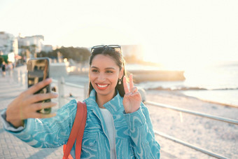 微笑时尚的有趣的女人旅游影响者采取自拍和平标志手势电话社会媒体<strong>视频</strong>调用照片探索旅行观光<strong>散步</strong>在户外
