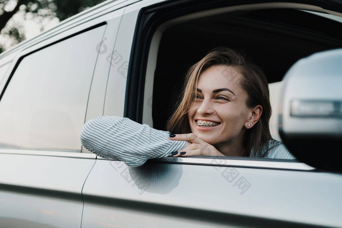 cheeful高加索人女人牙套系统享受路旅行车窗口