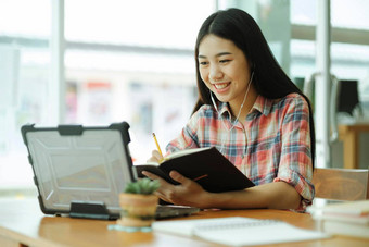 年轻的亚洲女人研究前面移动PC电脑耳机离<strong>线</strong>