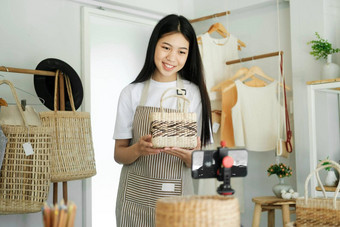 年轻的亚洲女商人时尚博主显示<strong>编织篮子</strong>产品微笑