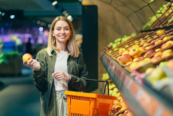 年轻的金发女郎女人选择选择水果蔬菜计数器超市